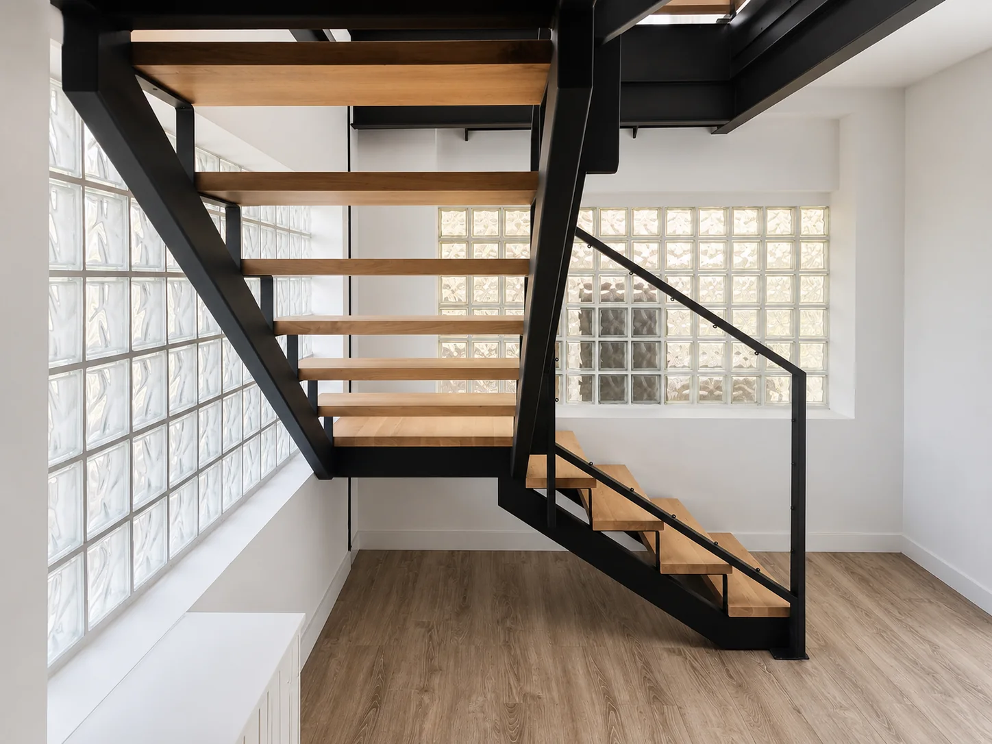 Detalle de escalera interior con estructura metálica negra y madera natural